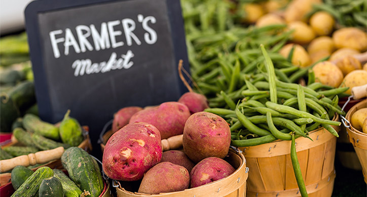 farmers market sign in front of vegetables